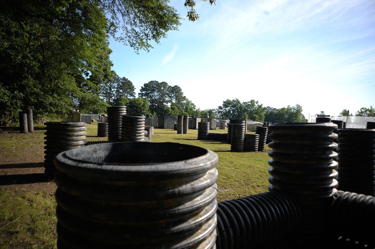 A paintball field with a lot of barrels and trees in the background.