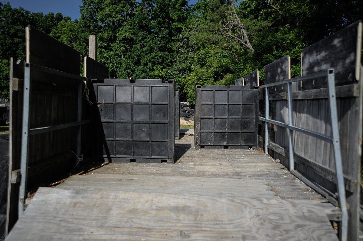 A wooden deck with a fence and a bunch of black containers on it.