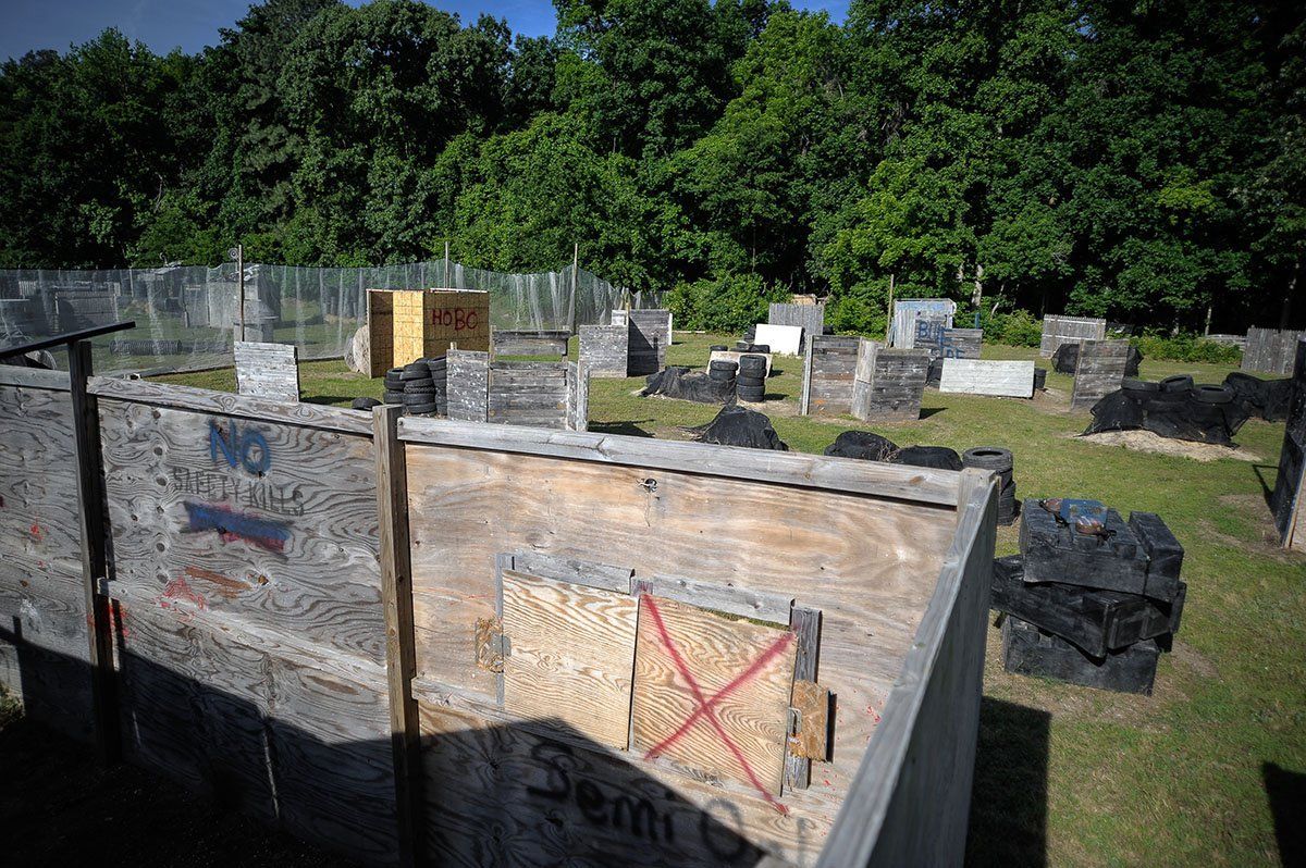 A paintball field with a wooden fence and trees in the background.