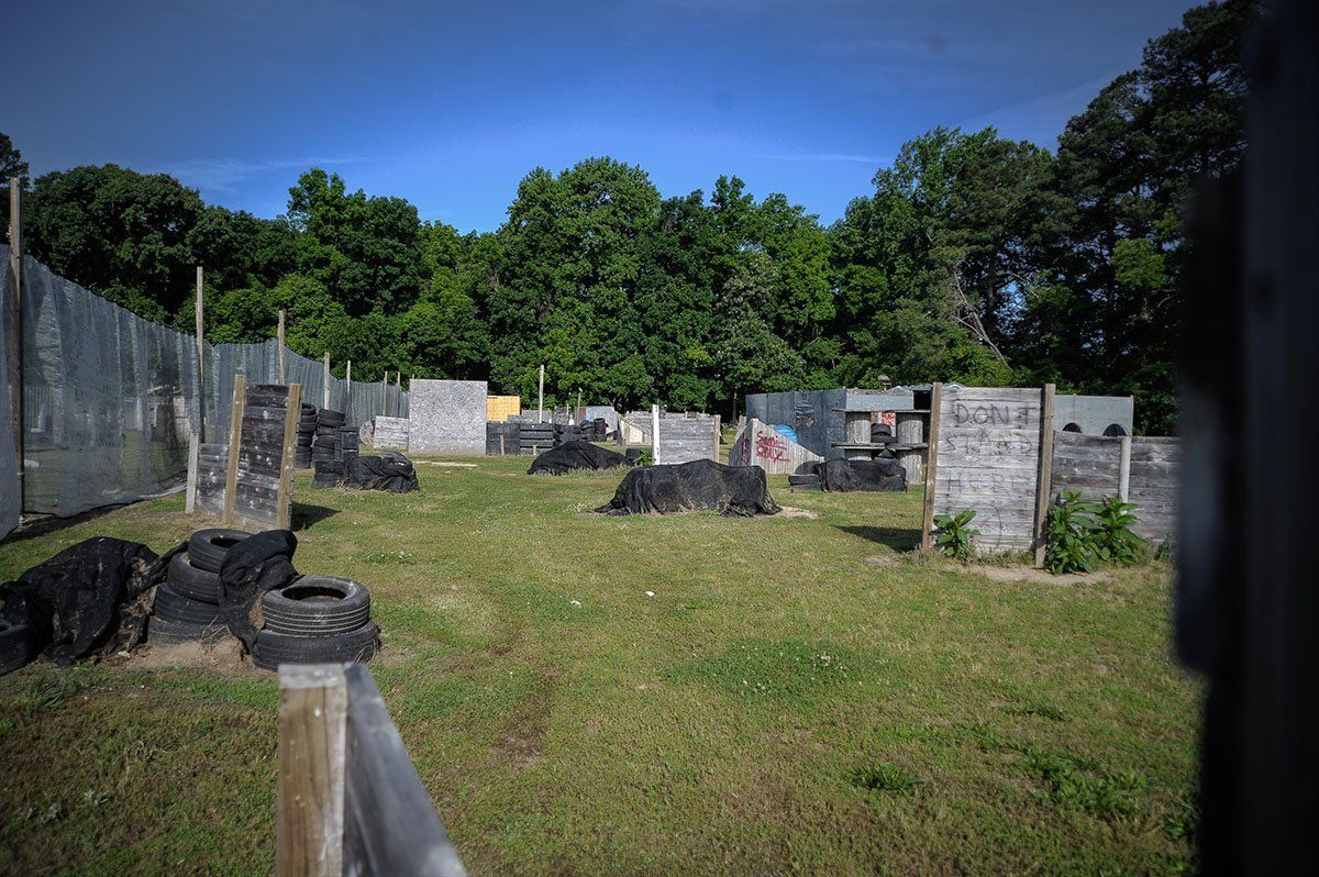 A paintball field with a fence and trees in the background.