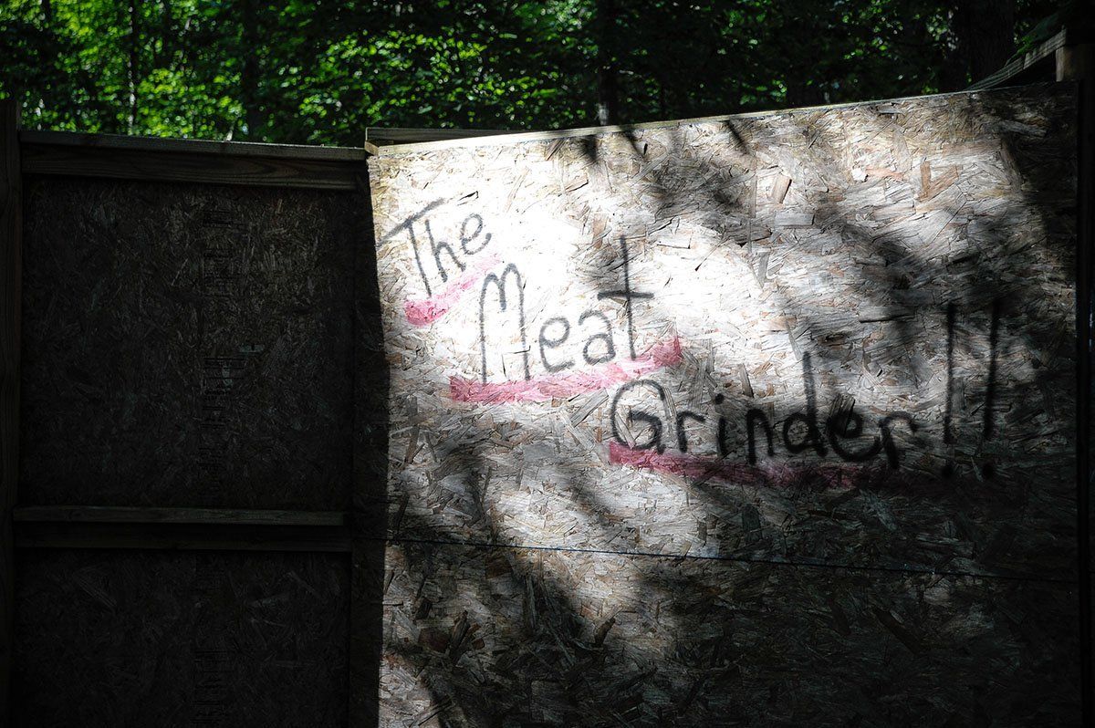 A concrete wall with graffiti on it that says the meat grinder