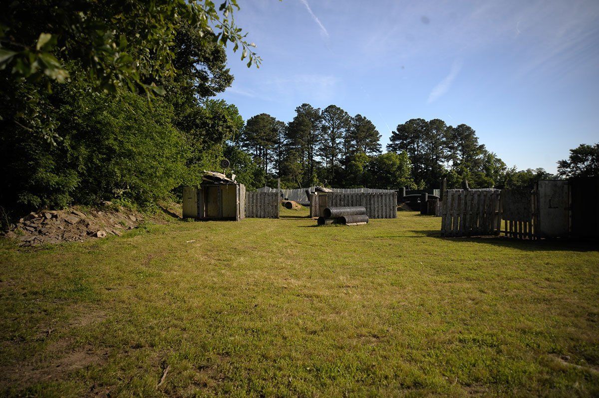 A large grassy field with a fence and trees in the background.