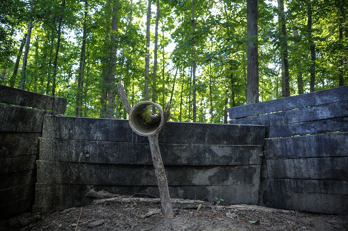 A wooden fence in the middle of a forest with trees in the background.