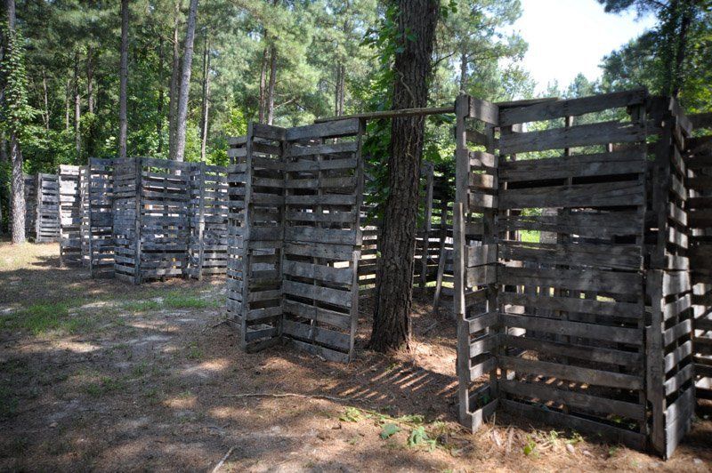 A bunch of wooden pallets are stacked on top of each other in a forest.