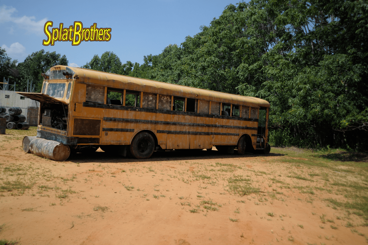 A yellow school bus is parked in a dirt field.