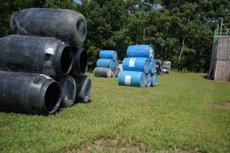 A bunch of barrels are stacked on top of each other in a field.