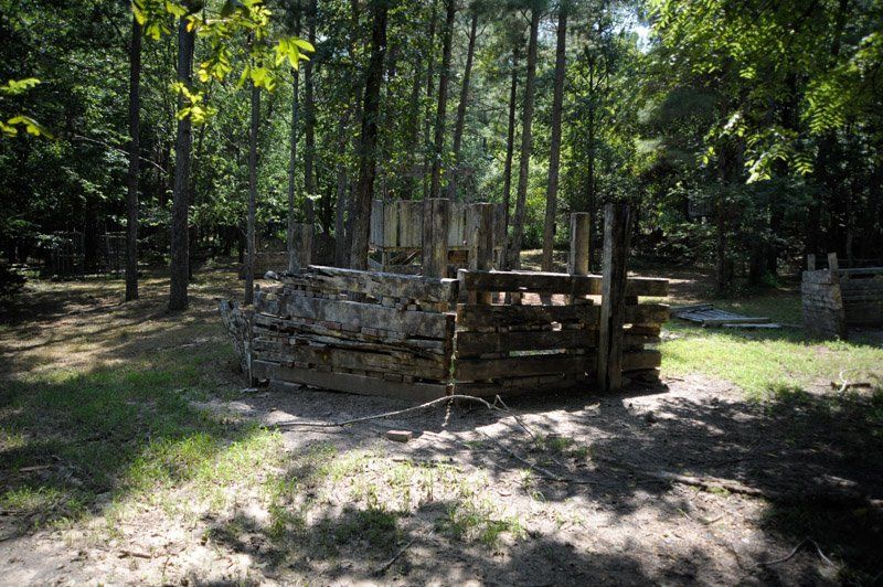 A wooden fence in the middle of a forest surrounded by trees.