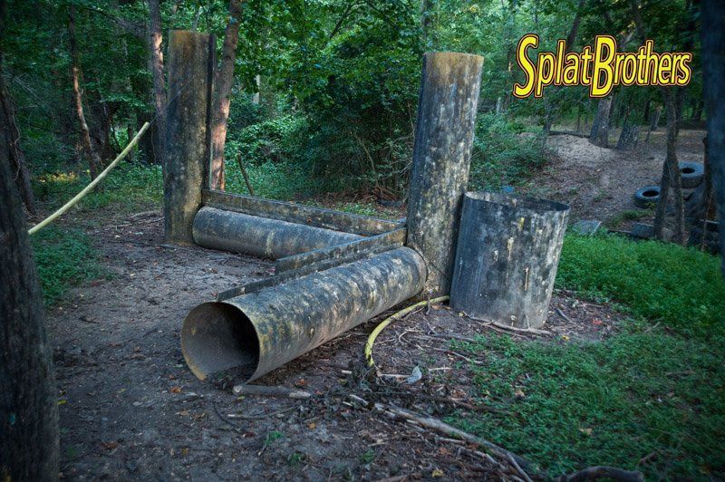 A bunch of pipes are laying on the ground in the woods.