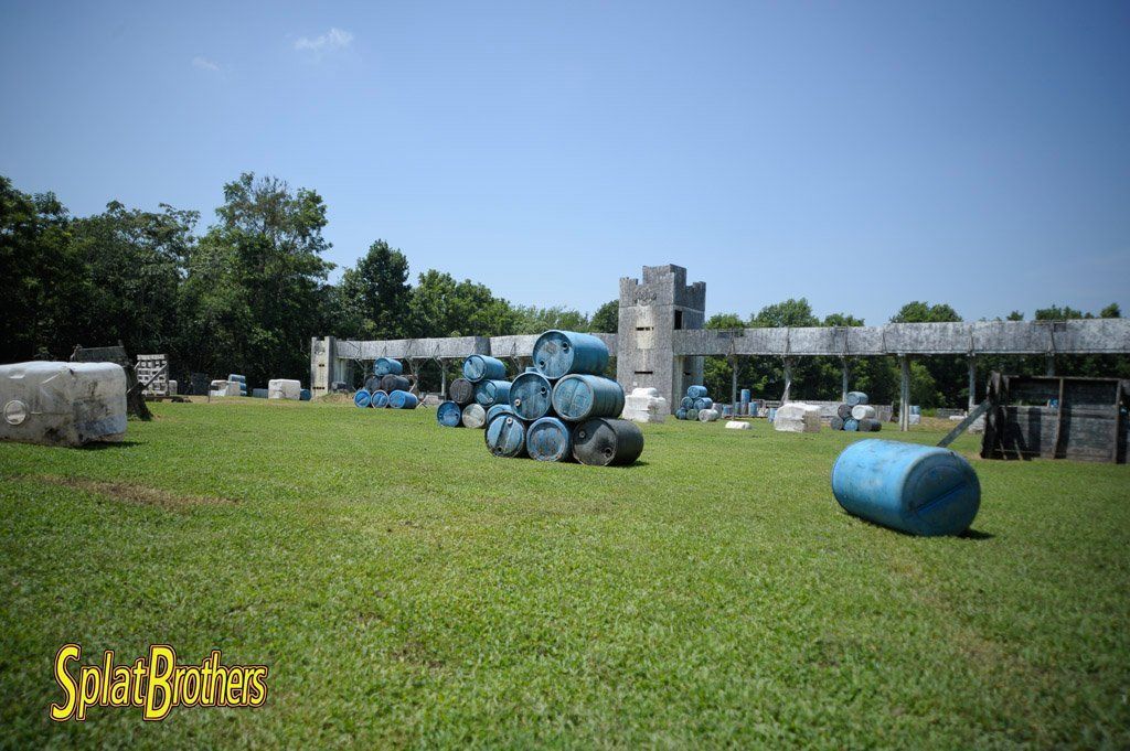 A paintball field with a bunch of blue barrels in the middle of it.