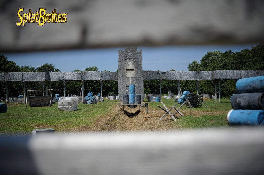 A view of a paintball field through a wooden fence.