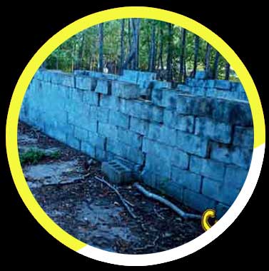 A blue brick wall in a yellow circle with trees in the background.