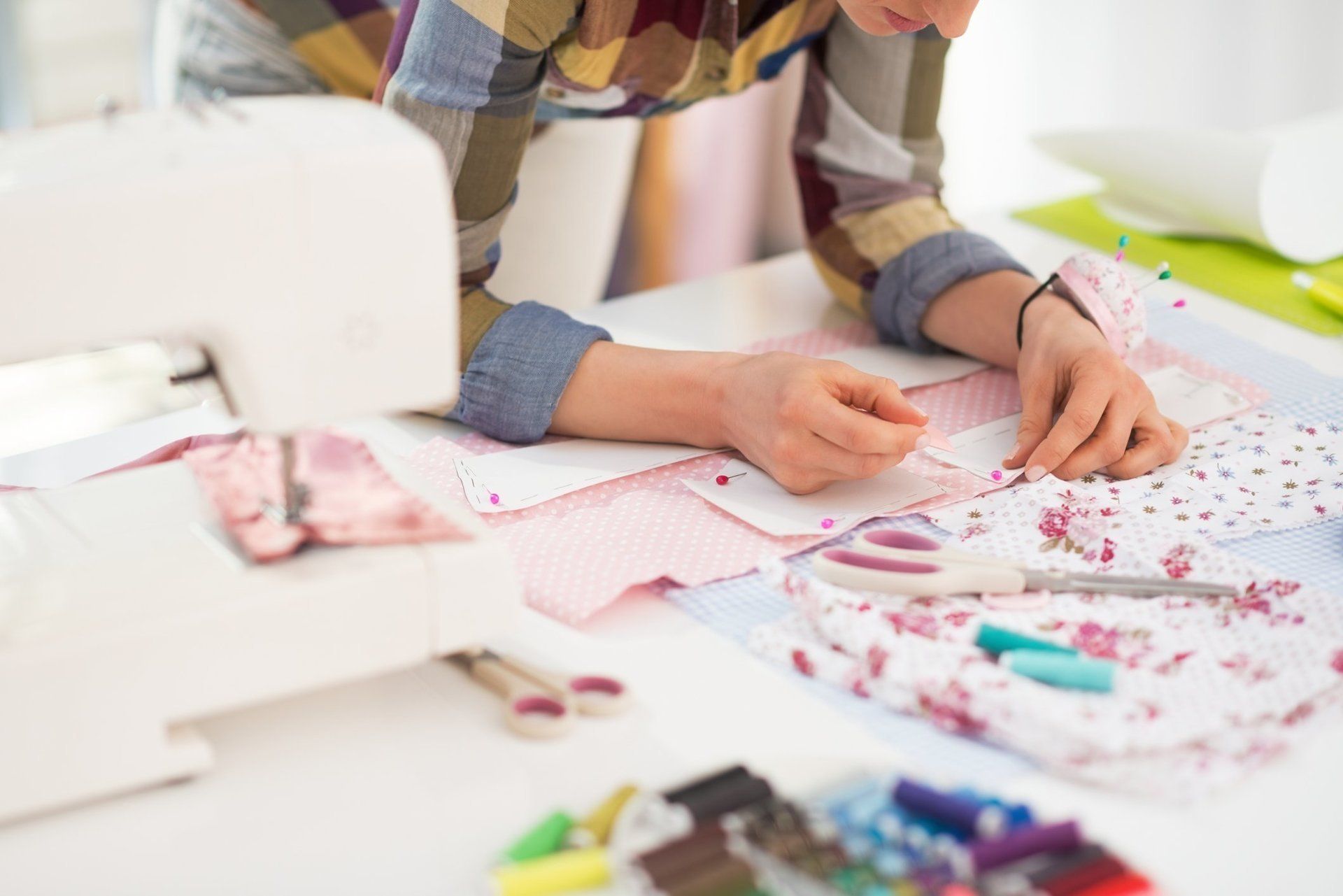 A woman is sitting at a table using a sewing machine.