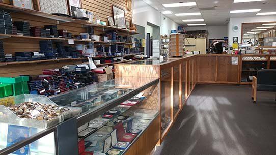 Interior shot of a store with display cases, shelves of merchandise, and a wooden counter.