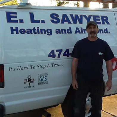 Man standing by a white van with E.L. Sawyer Heating and Air logo, with 