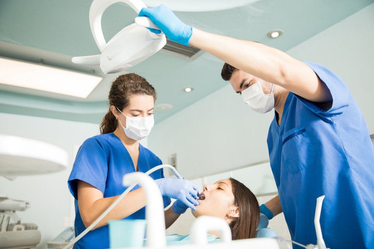 Dentist and assistant examining patient's teeth in a dental clinic.
