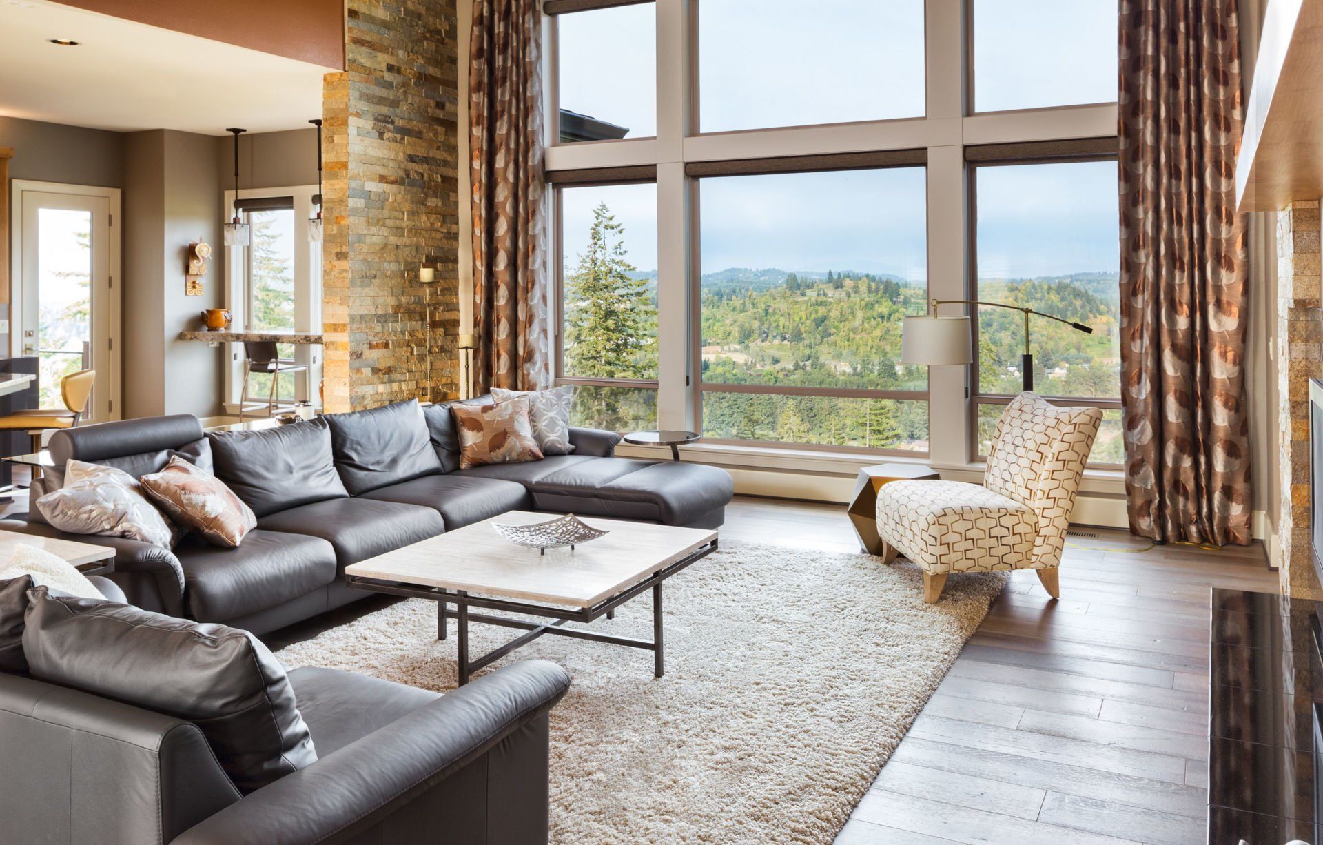 A living room with a couch , chair , coffee table and large windows.
