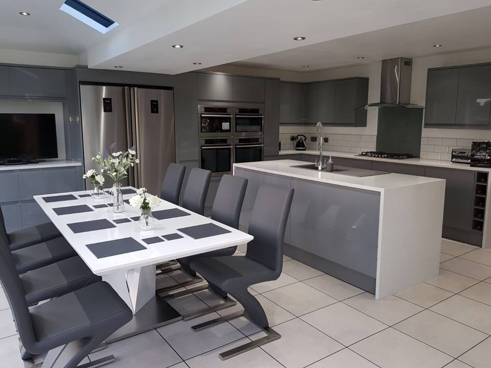 The same large, modern, newly-fitted kitchen from the reverse angle, with an 8-seater modern dining table in the foreground.