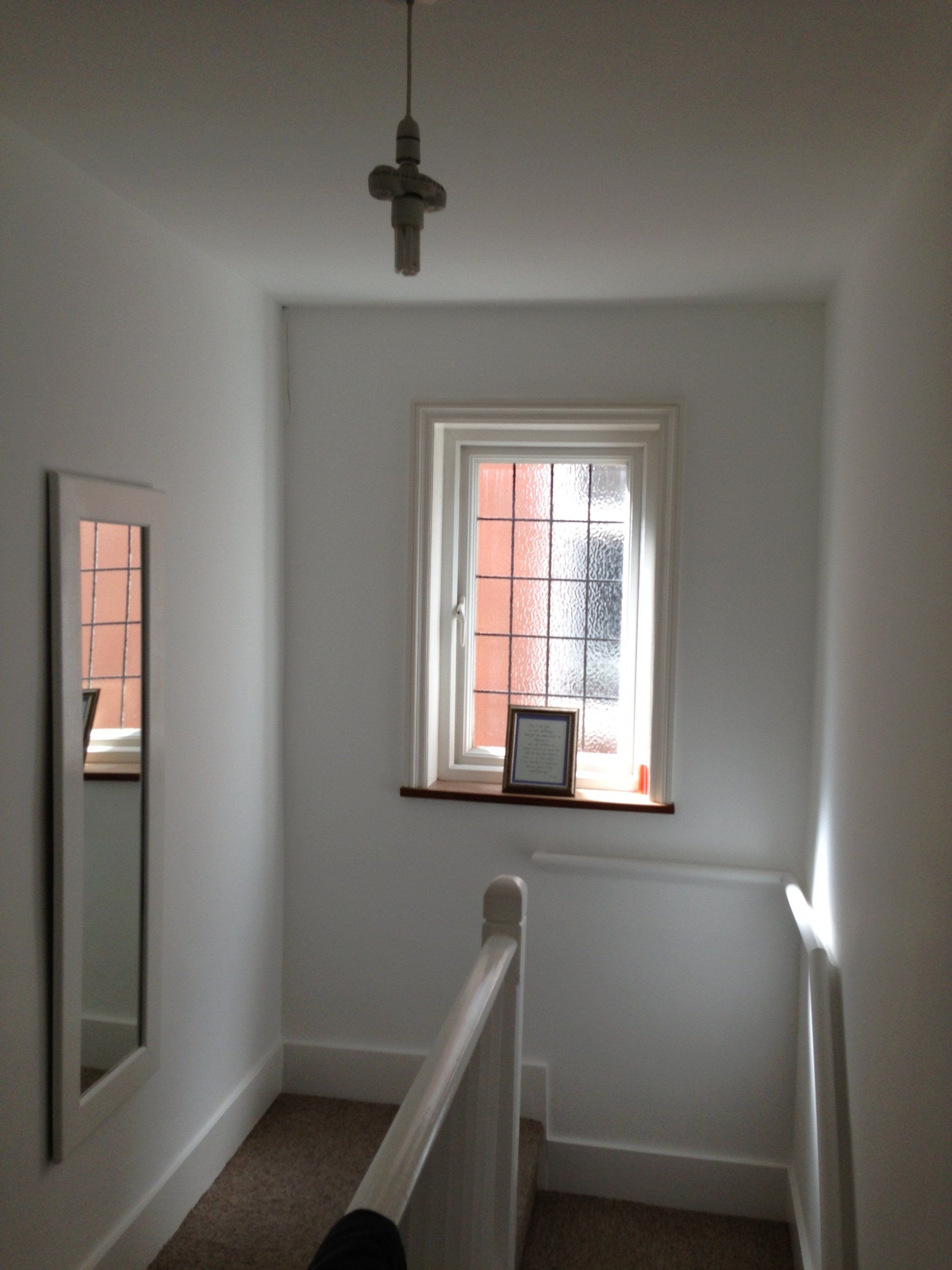 A freshly plastered and painted hallway - crisp white walls at the top of a staircase.