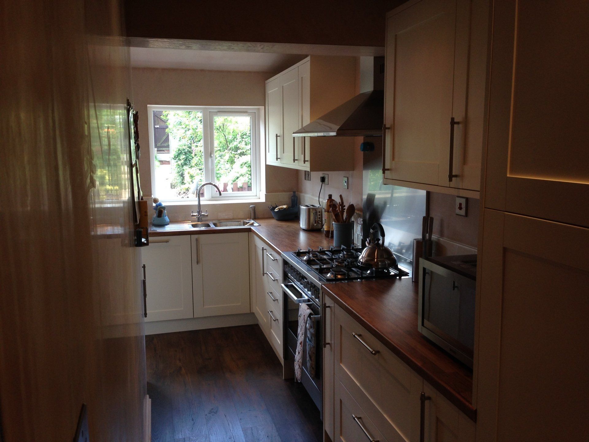 A modern kitchen installation, with light cream cupboard fronts and dark wood counter tops.