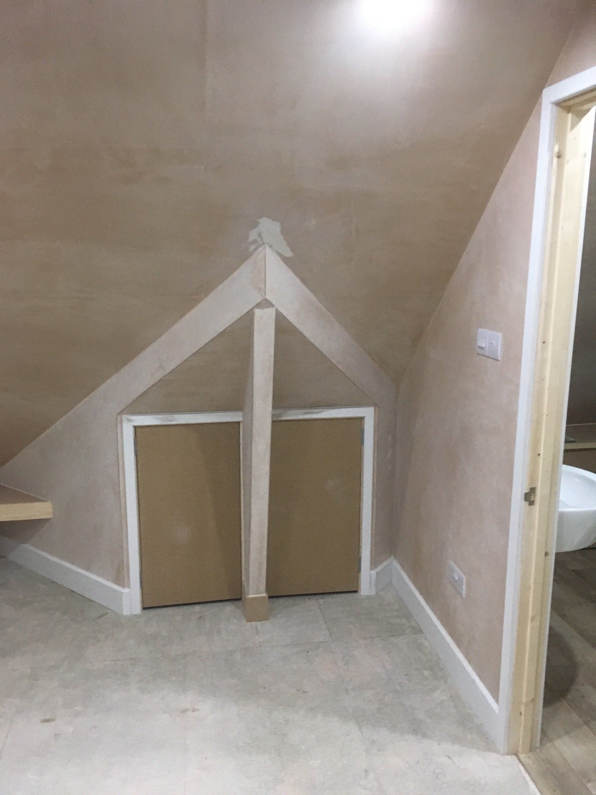 A newly converted and plastered loft or attic space with fitted cupboards.