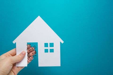 Hand with funny fingers holding white paper house figure on