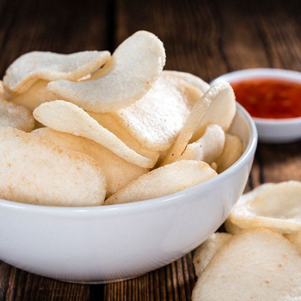 A bowl of prawn chips next to a bowl of dipping sauce