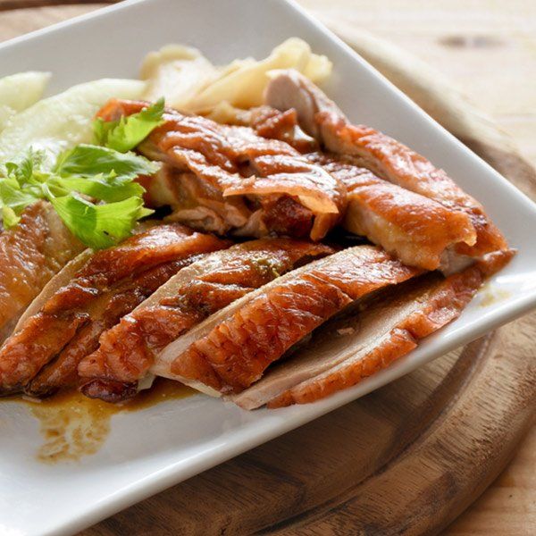 A white plate topped with sliced meat and vegetables