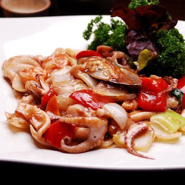 A white plate topped with squid and vegetables