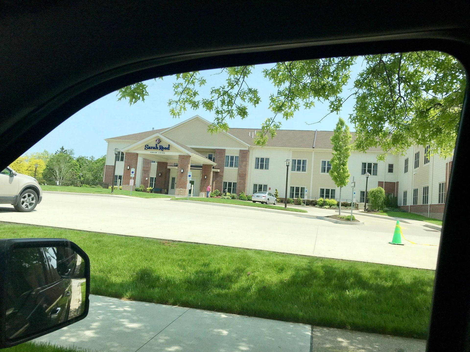 A car is parked in front of a large building.