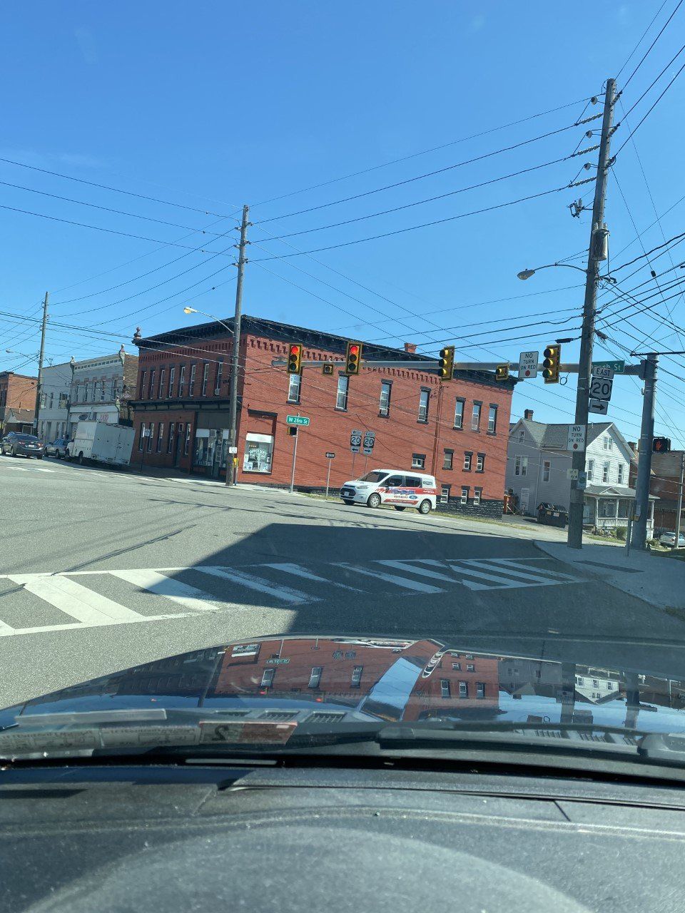 A car is driving down a street with a red building in the background
