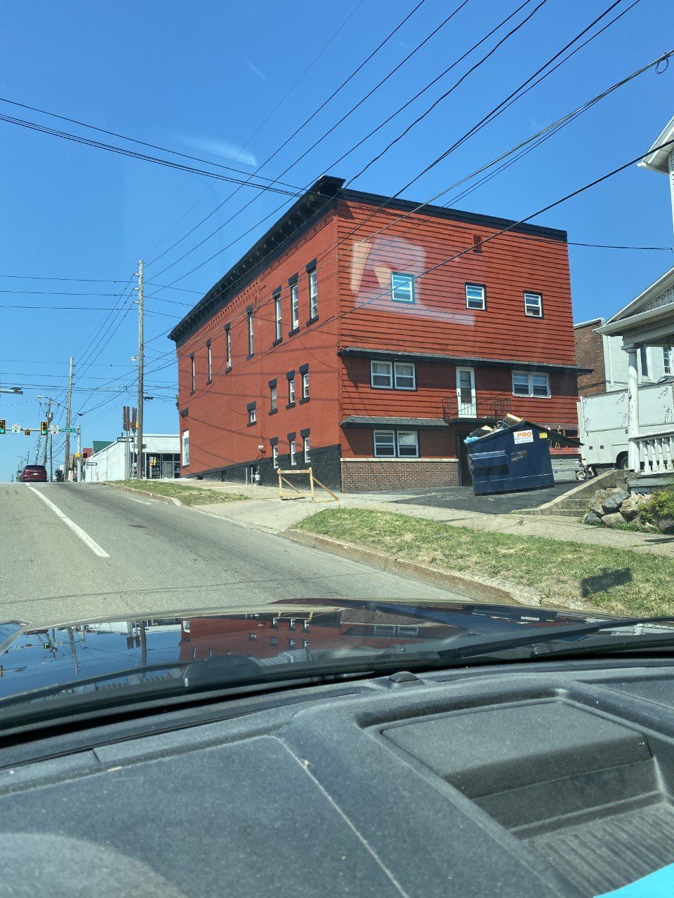 A car is driving down a street with a large red building in the background