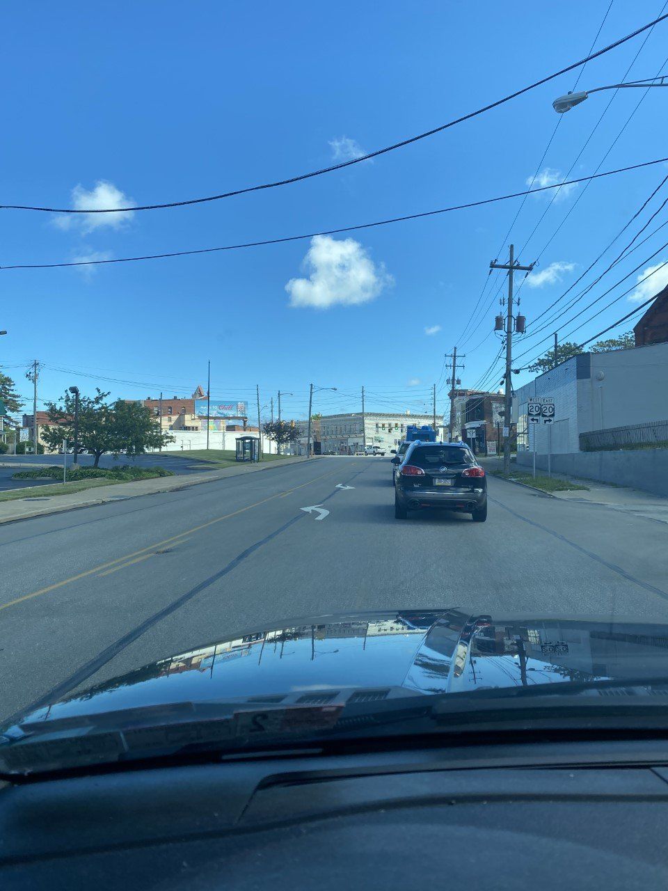 A car is driving down a street with a blue sky in the background