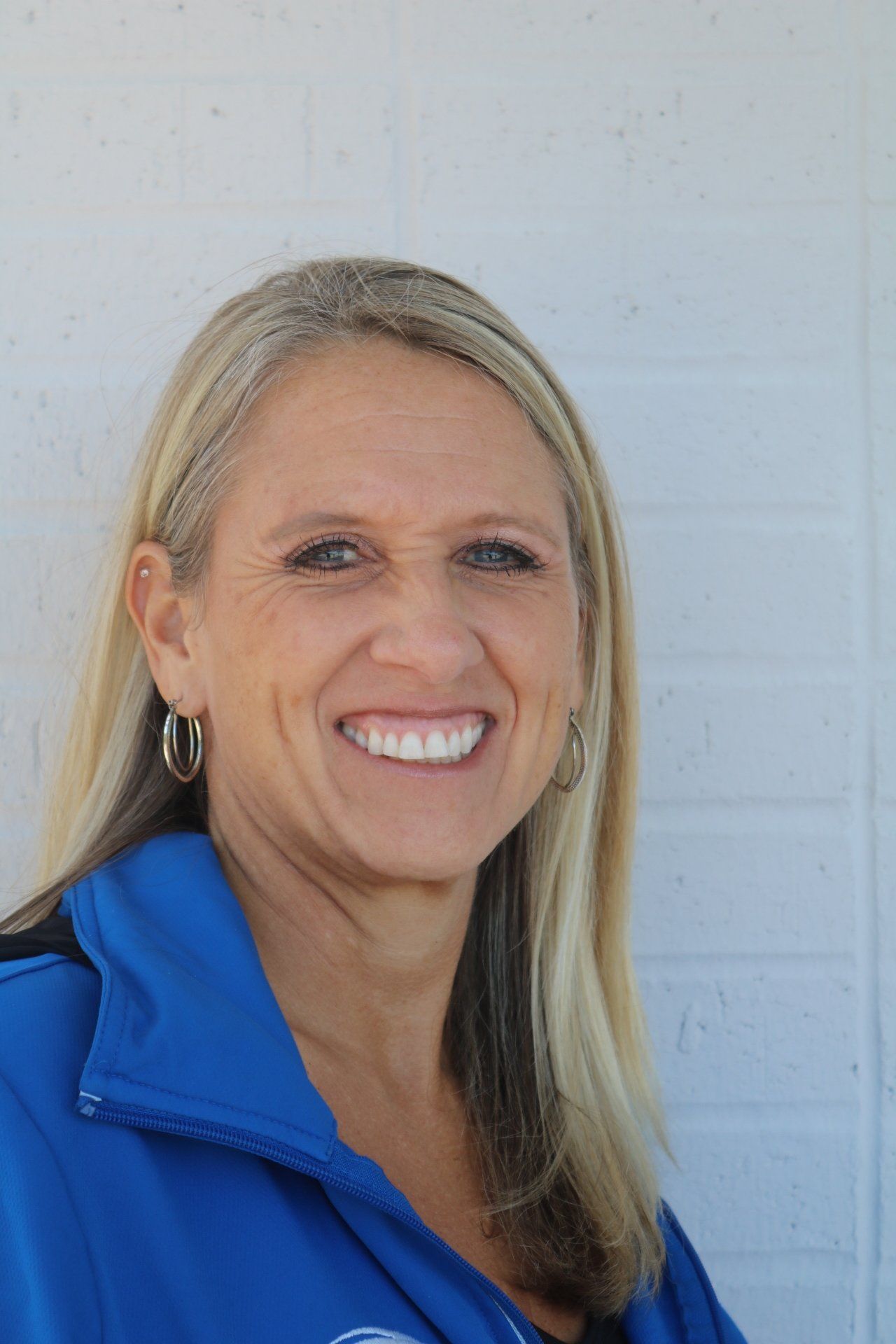 A woman in a blue jacket is smiling for the camera.