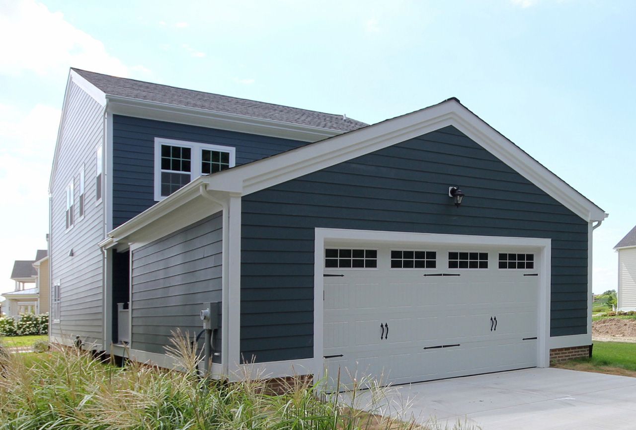 A blue house with a white garage door in front of it.