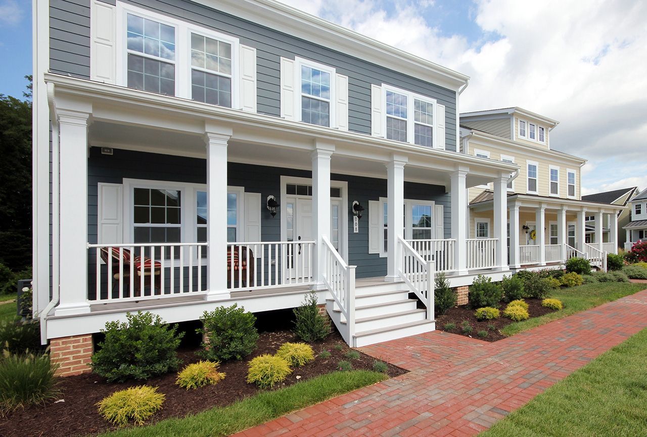 A row of houses with porches are lined up on a brick sidewalk.