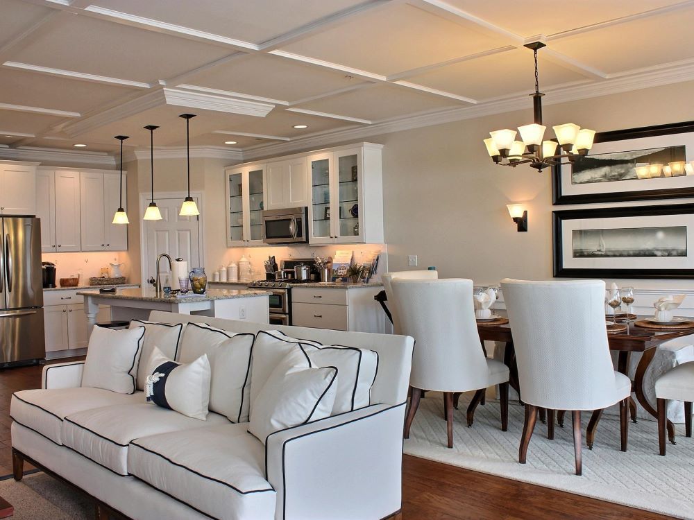 A living room with a couch and chairs and a kitchen