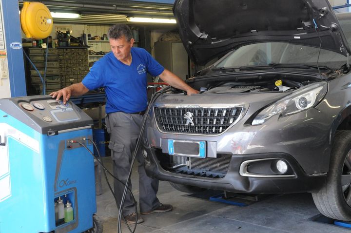 Un meccanico utilizza un tester per le emissioni su un SUV grigio in un'officina.