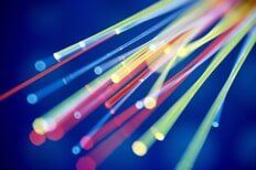 Colorful fiber optic cables against a dark blue background, transmitting data.