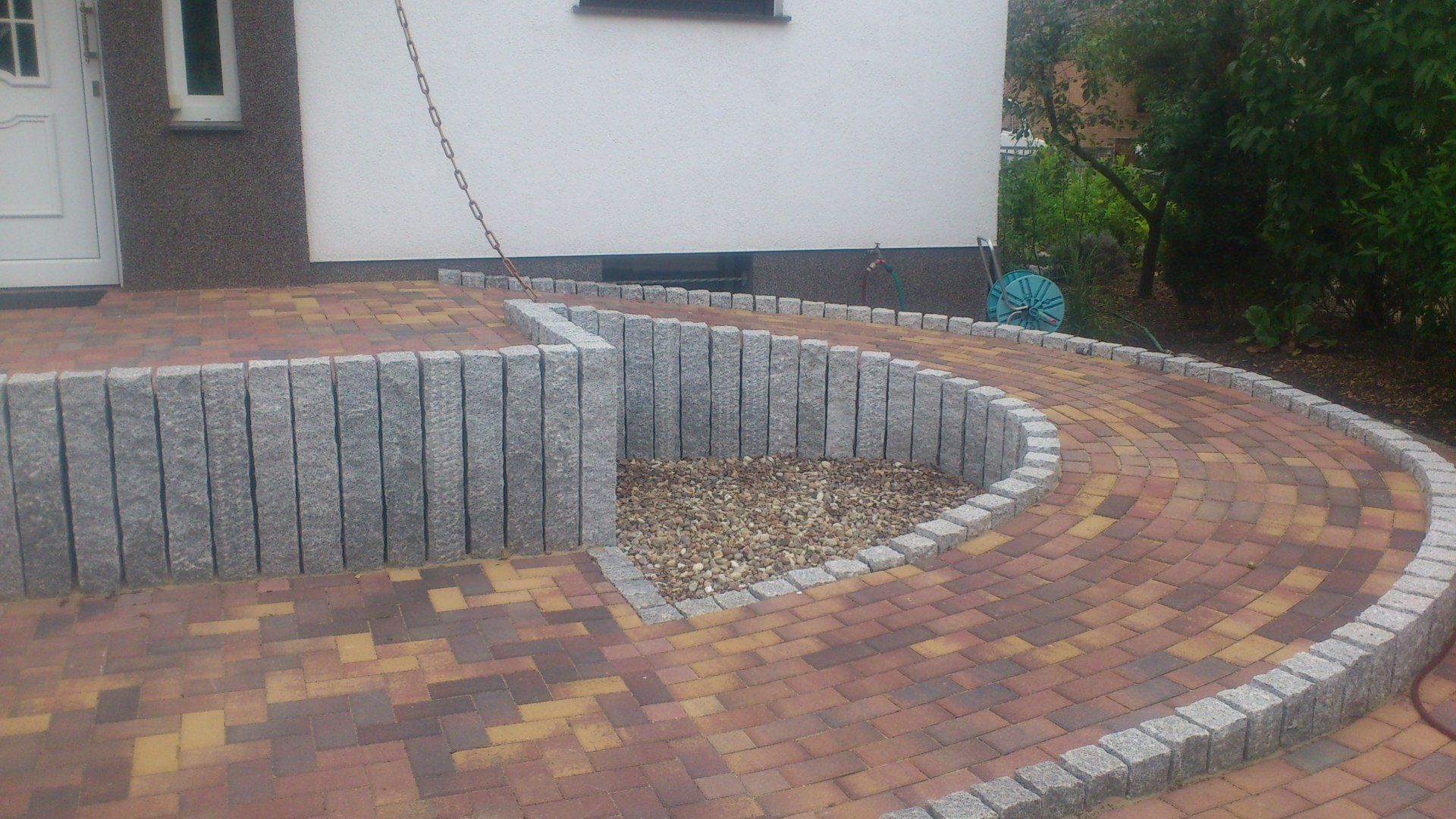 Vor einem Haus wird eine gepflasterte Auffahrt gebaut.