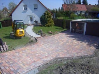 Vor einem Haus parkt ein gelber Bagger.