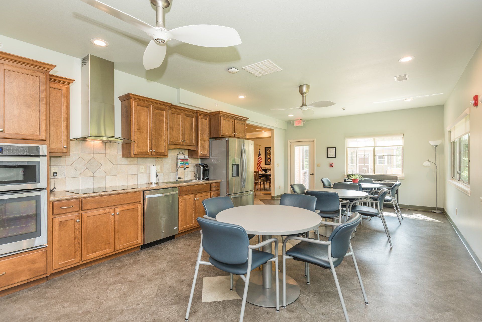 A kitchen with tables and chairs and a ceiling fan.