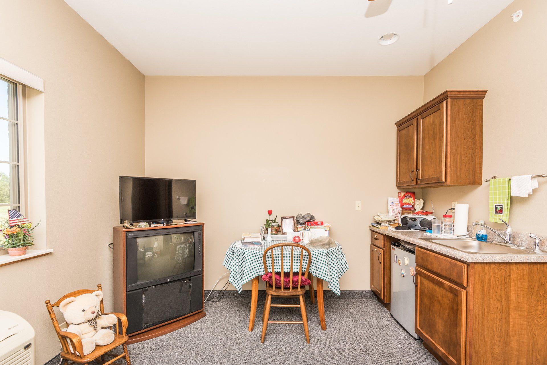 A living room with a table and chairs, a television, and a kitchen.