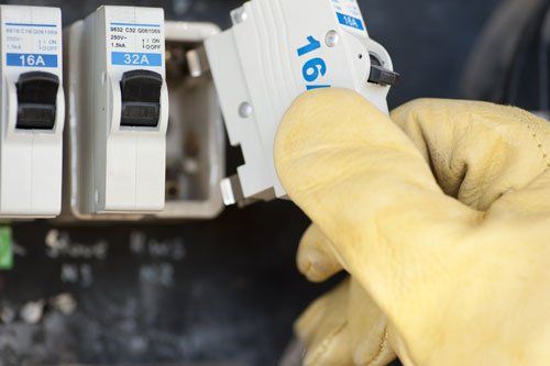 Electrician at switch board at house exchanging fuse.
