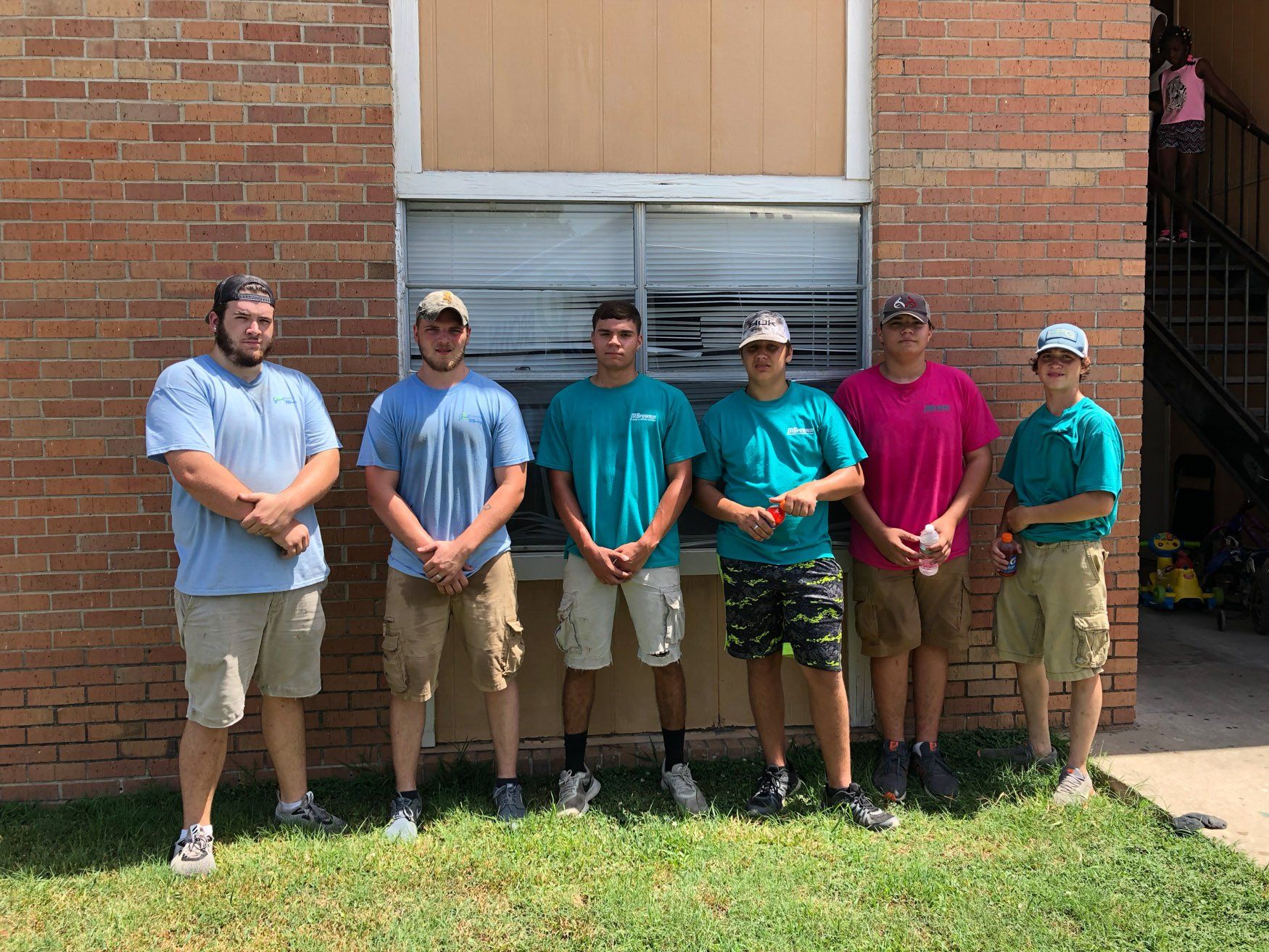 A group of young men standing in front of a brick building.