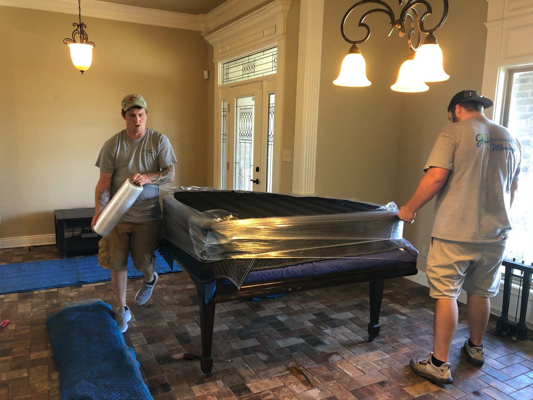 jr brown employees wrapping a piano for moving