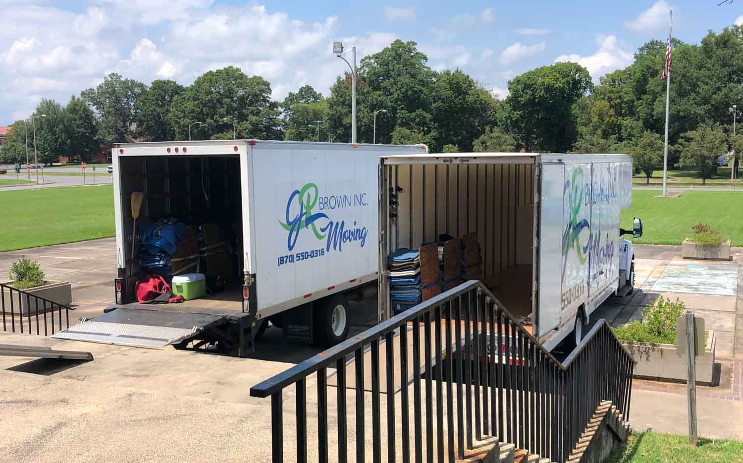 Two moving trucks are parked next to each other in a parking lot.