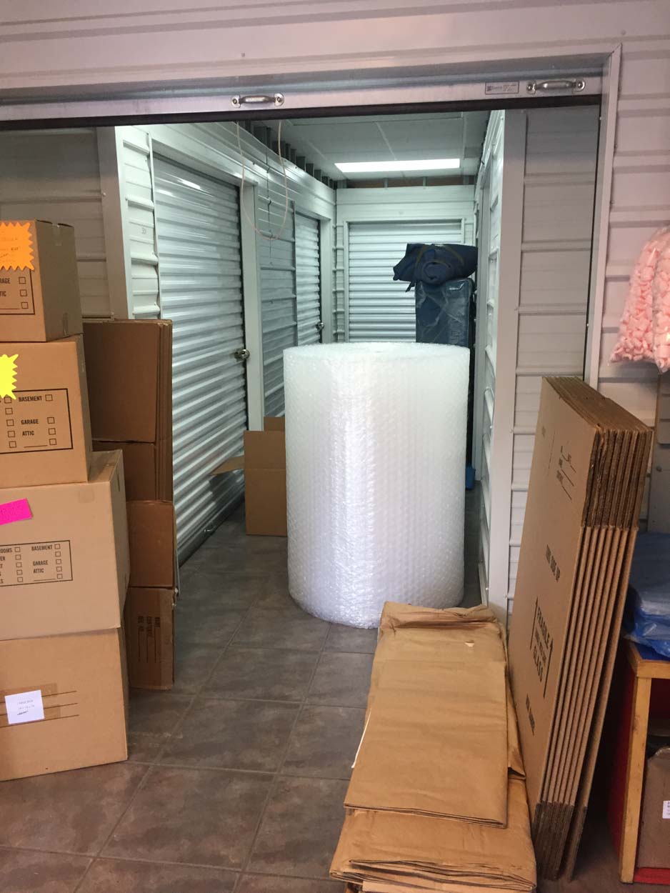 A room filled with boxes and a roll of bubble wrap.