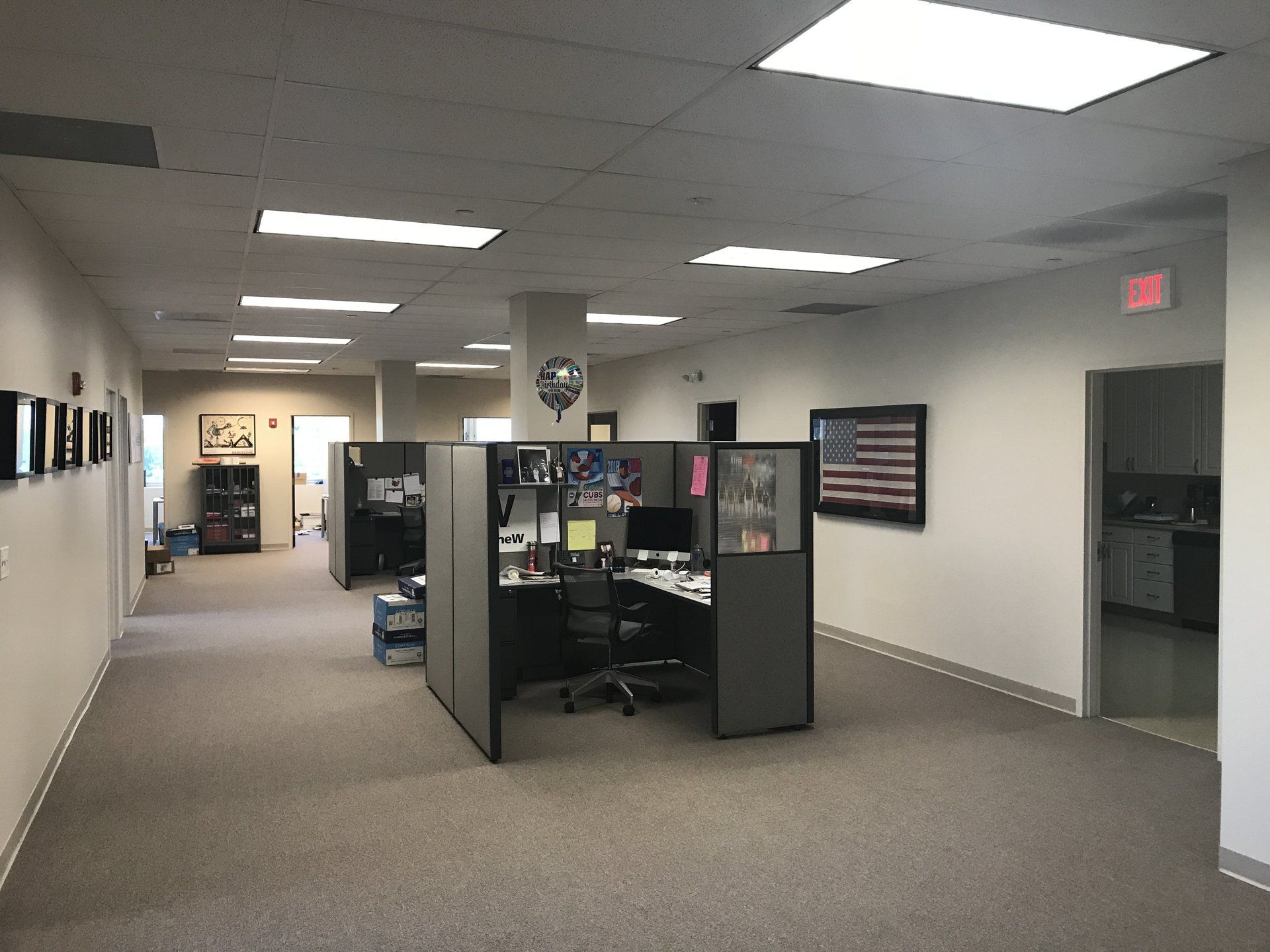 An office with cubicles and an american flag on the wall