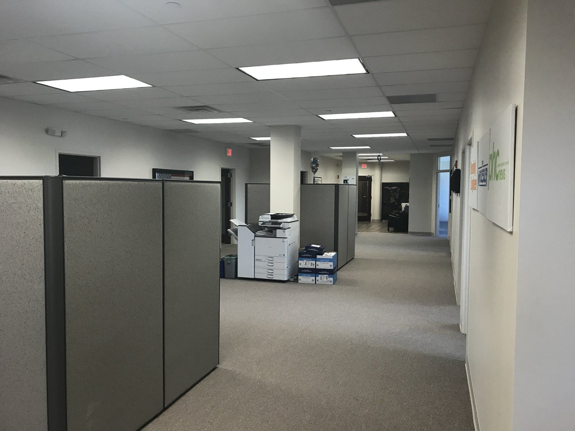 A hallway in an office with cubicles and a printer