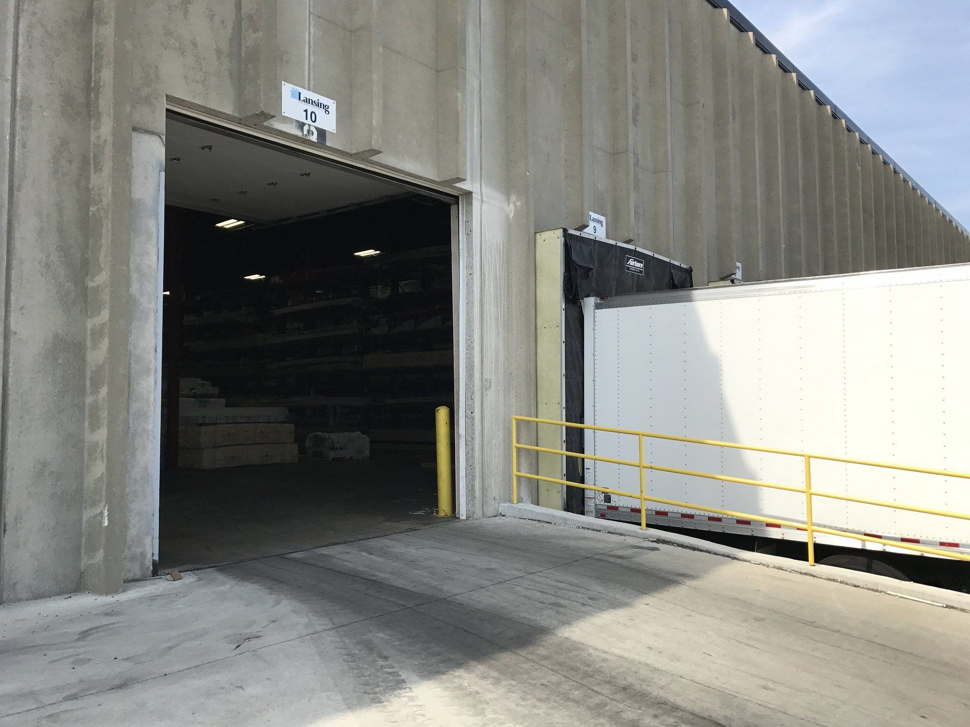 A truck is being loaded into a warehouse with the door open.